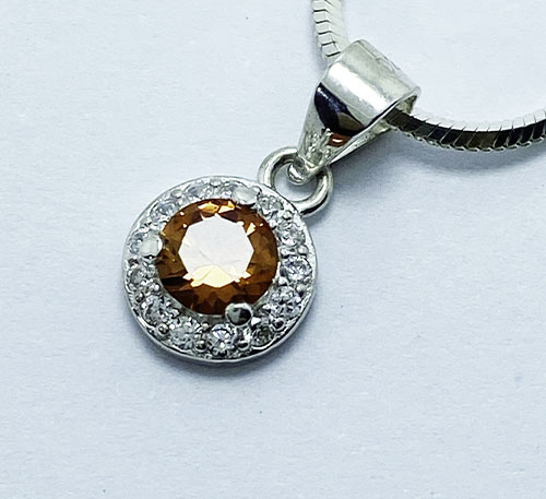 Dije de plata ley 0,925 con citrino natural , talla redonda de diámetro 6 mm y 1 quilate de peso. Diseño de uñas con circones de 1,0 mm de diámetro