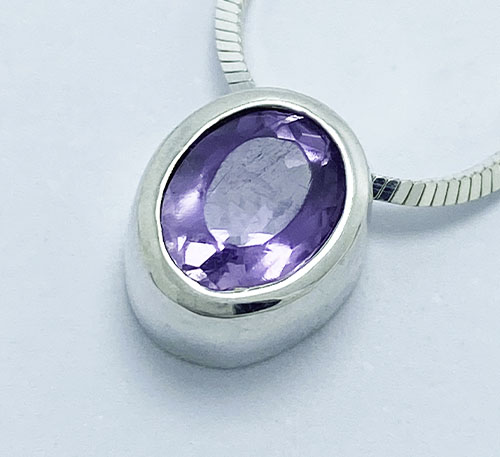 Dije de plata ley 0,925 peso 1,5 gramos con amatista natural, talla redonda de tamaño 8 mm de diámetro y 2 quilates de peso.